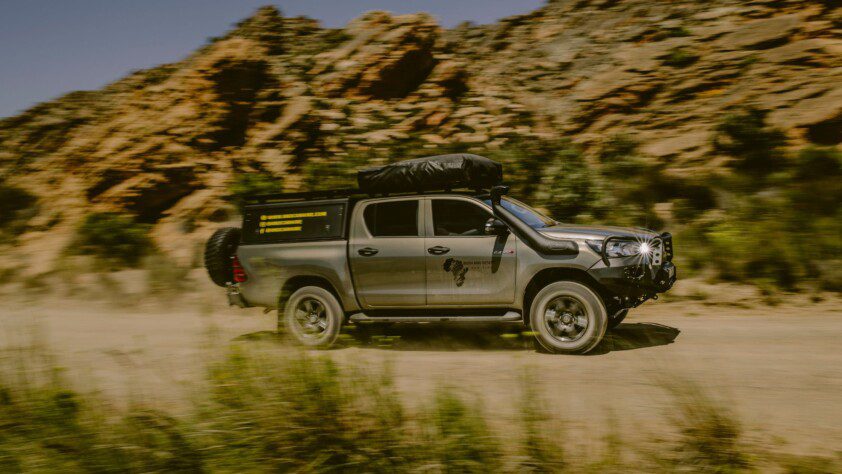 Bush and Desert Car Hires' robust 4x4 vehicle navigating a rugged African terrain.