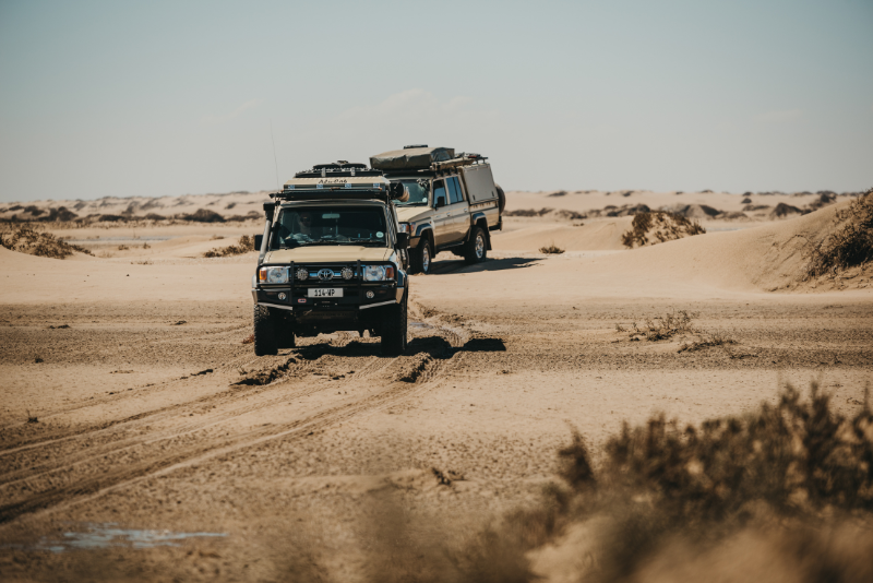 Fully equipped 4x4 vehicles driving on a dirt road in Botswana.