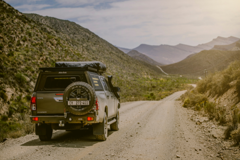 Fully equipped 4x4 car hire in Botswana on a scenic dirt road surrounded by rugged mountains, ideal for overland safaris.