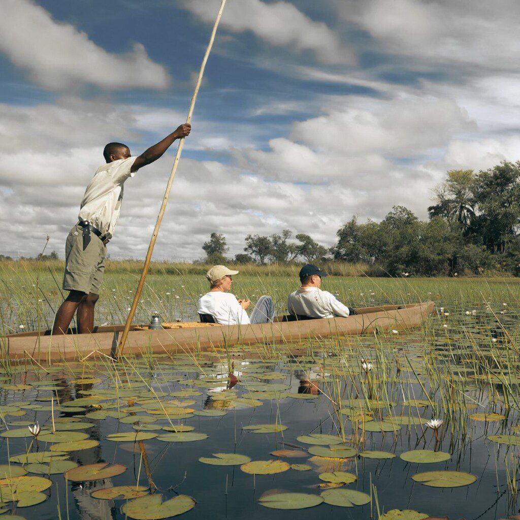 Travellers in a mokoro canoe on the Okavango Delta, a serene 4x4-supported adventure.